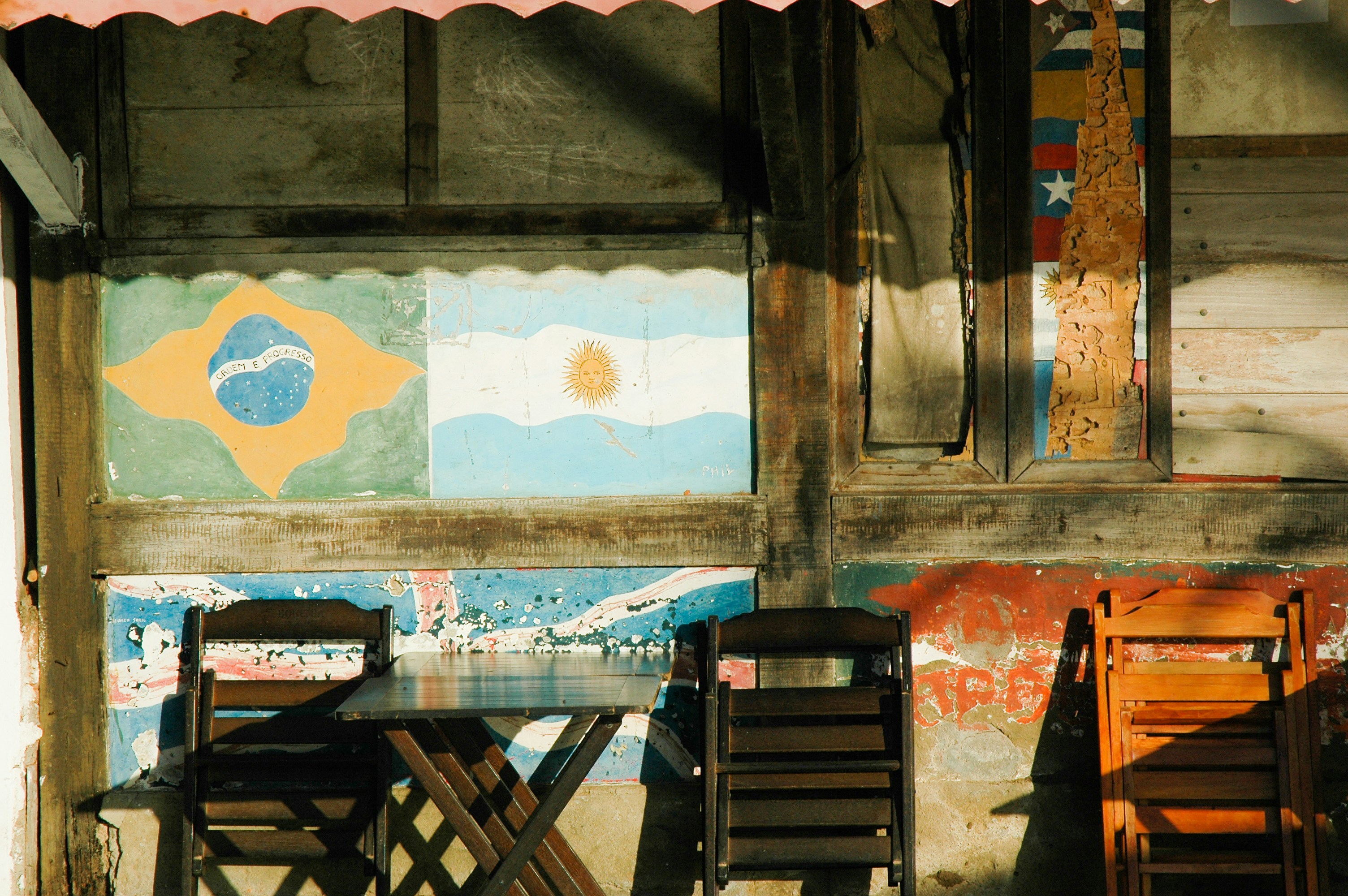 Decorative photo of sunlit external wall with flags table and chairs in Rio de Janiero, Brasil.