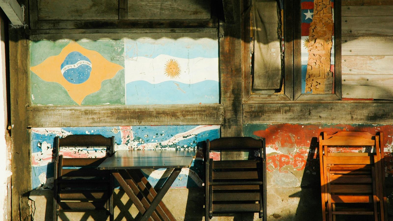 Decorative photo of sunlit external wall with flags table and chairs in Rio de Janiero, Brasil.